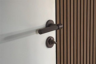Poignée de porte Helix 200 en bronze foncé montée sur une porte